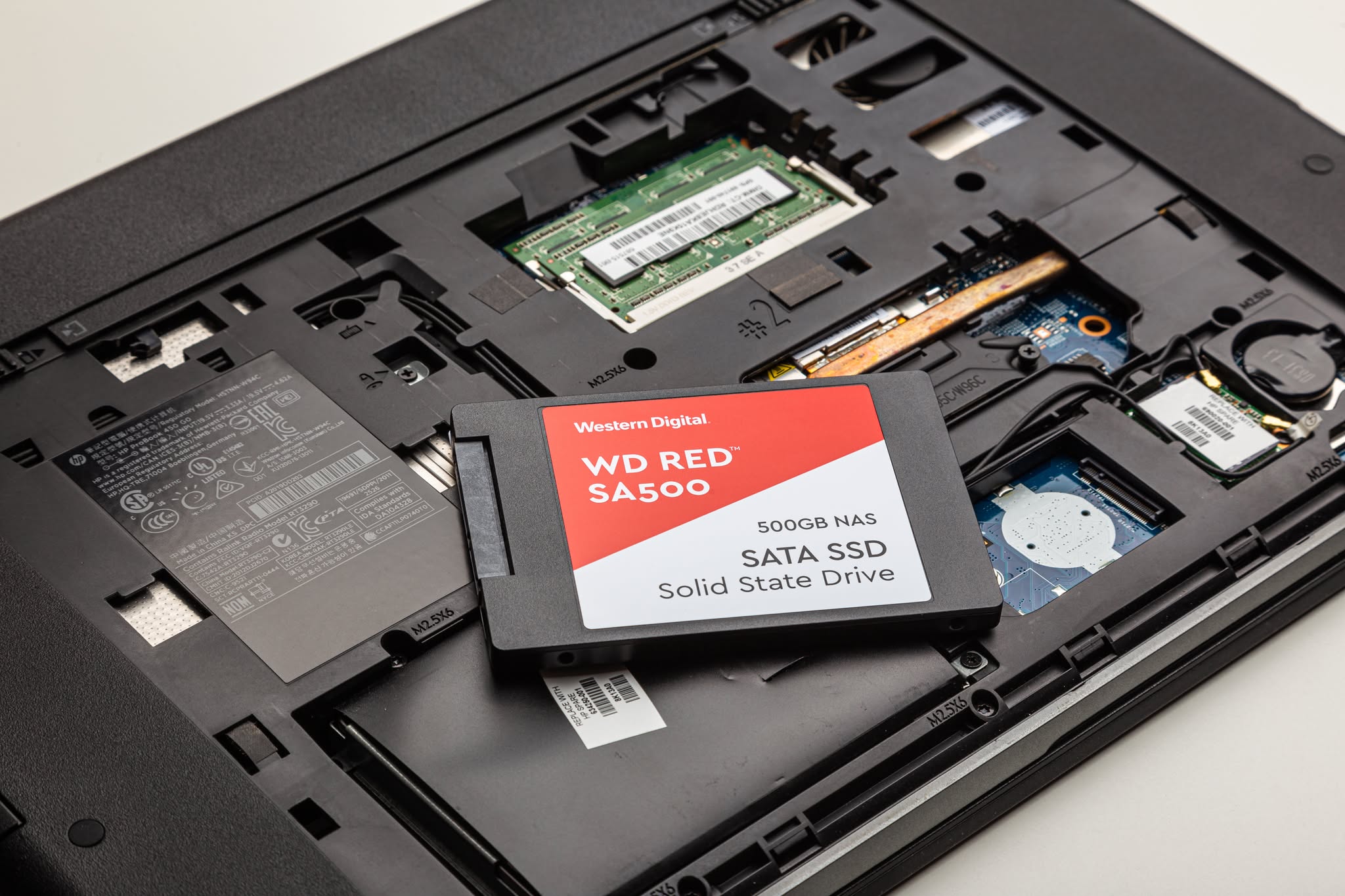 Unidad SSD SATA de 2,5 pulgadas junto a un portátil abierto